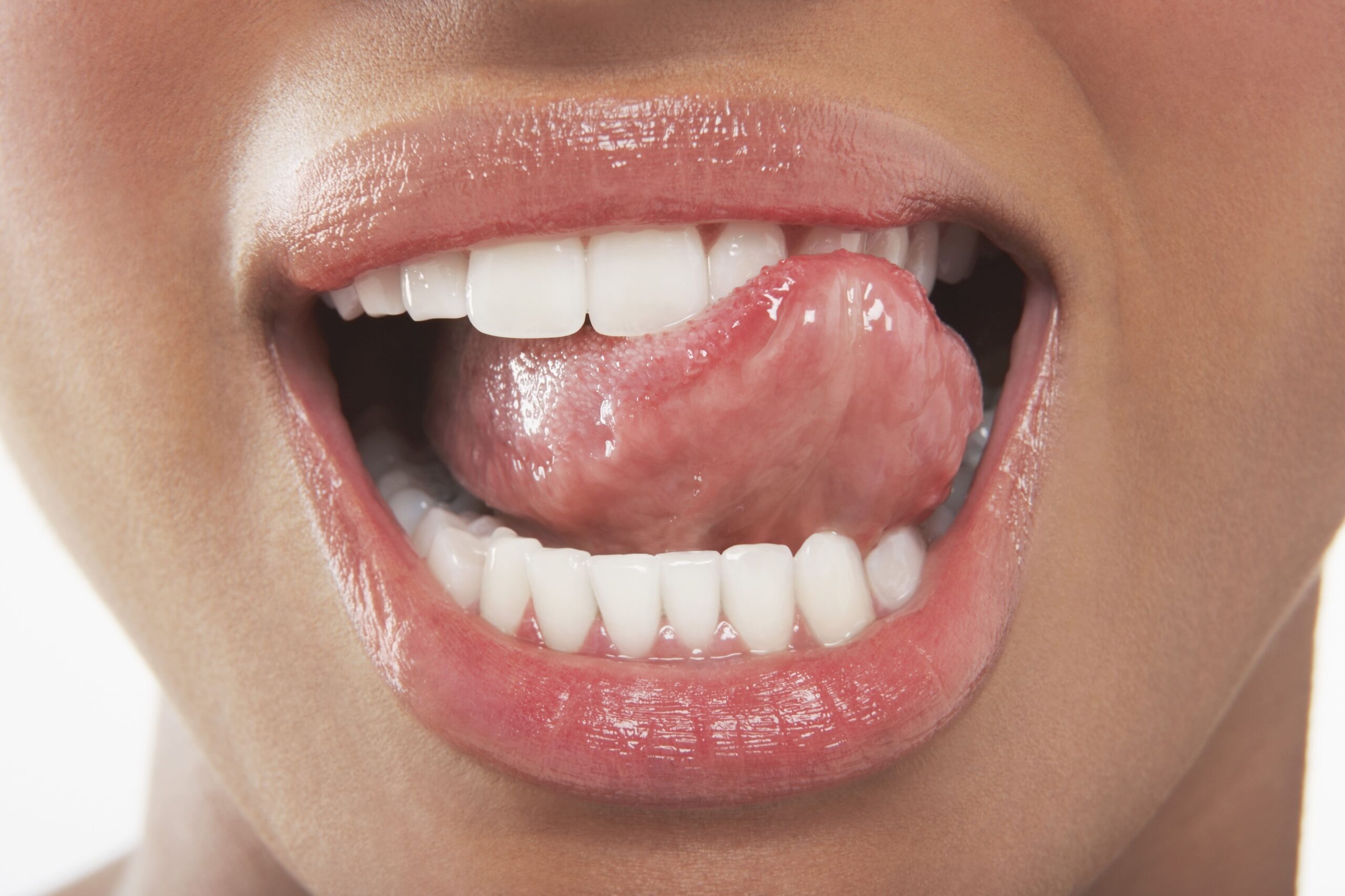 Close-up of woman running tongue over front teeth