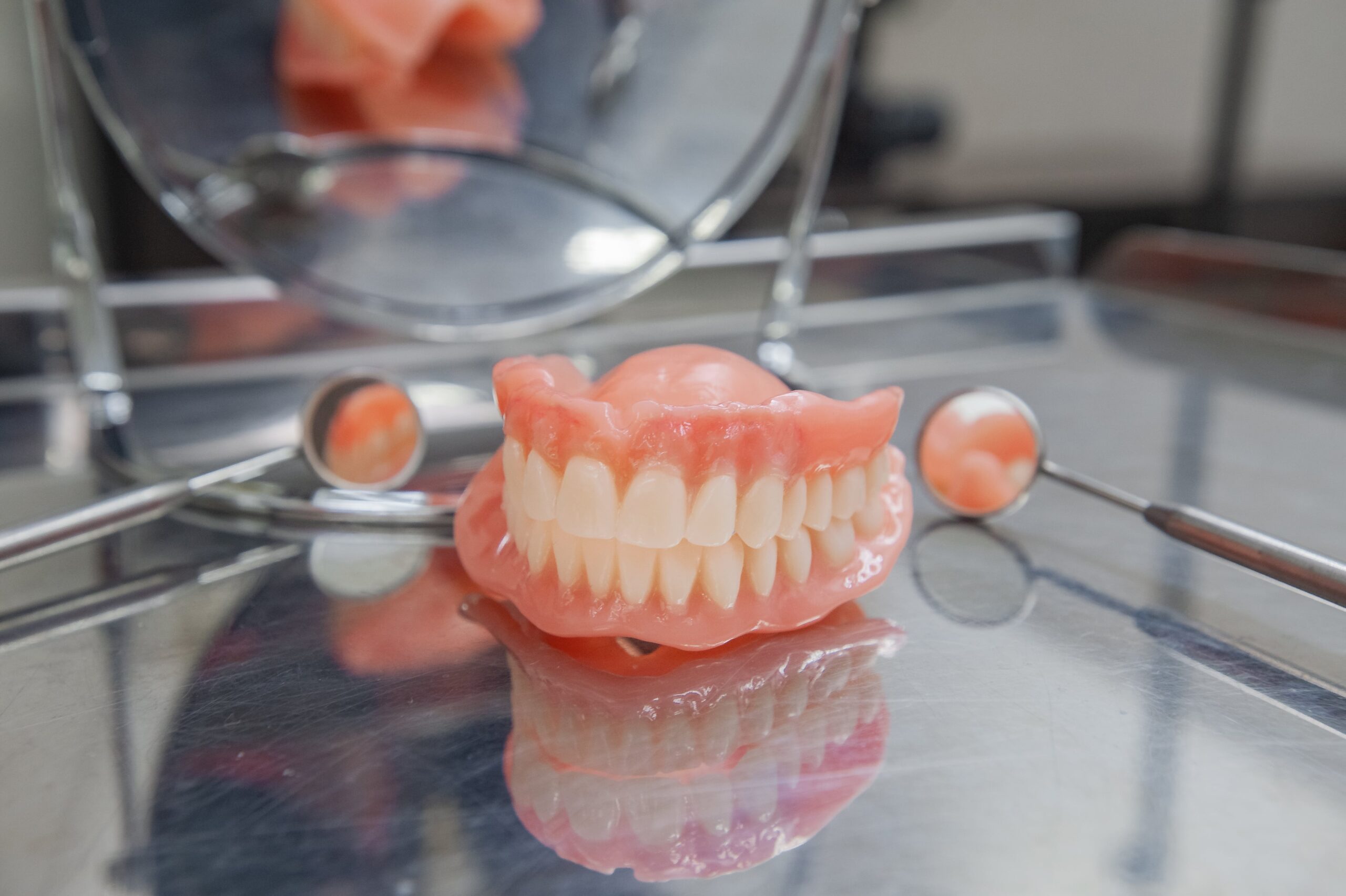 Dentures on metal tray beside dental tools