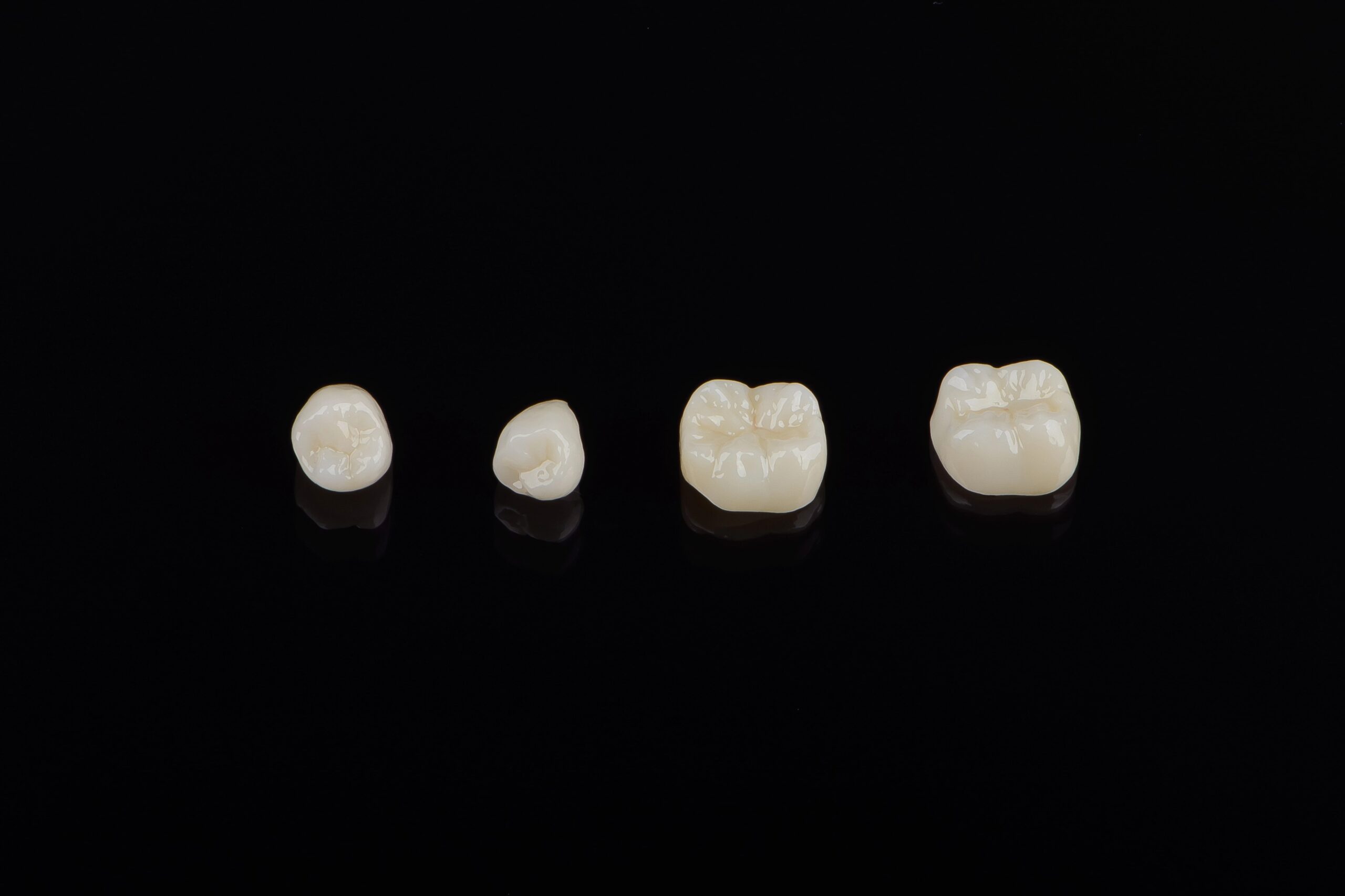 Four dental crowns on black background